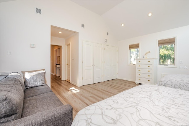 bedroom featuring a closet, high vaulted ceiling, and light wood-type flooring