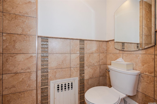 bathroom with radiator heating unit, toilet, and tile walls