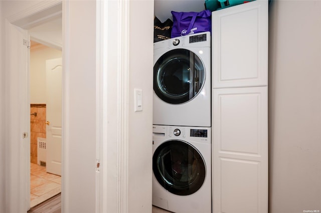 laundry area featuring cabinets, light hardwood / wood-style floors, and stacked washer and clothes dryer