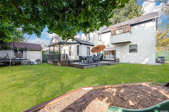 back of property featuring central AC, a yard, a trampoline, and a deck