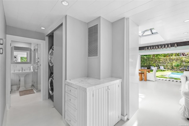 corridor with a healthy amount of sunlight, sink, and stacked washer and clothes dryer