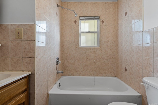 full bathroom featuring tiled shower / bath, vanity, toilet, and tile walls