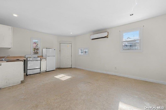 unfurnished living room with an AC wall unit, sink, and light colored carpet