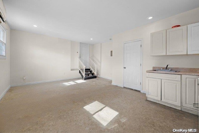 unfurnished living room with light colored carpet and sink