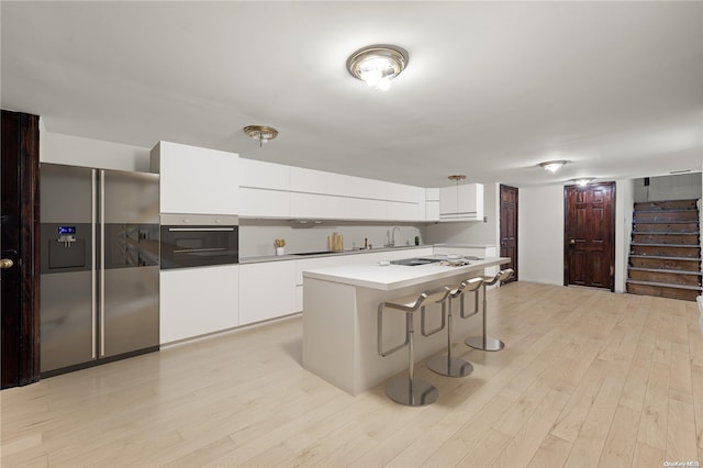 kitchen featuring white cabinets, appliances with stainless steel finishes, a center island, and light wood-type flooring