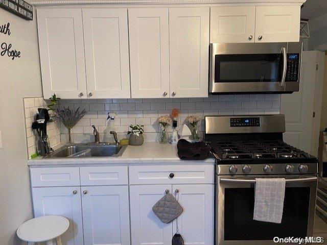 kitchen featuring backsplash, white cabinets, and appliances with stainless steel finishes