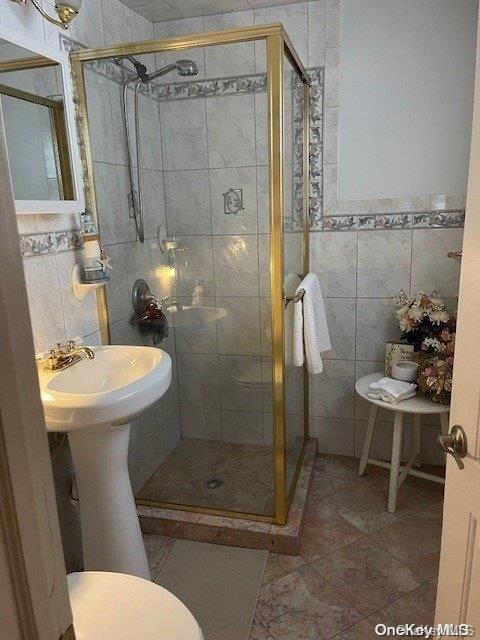 bathroom with tile patterned floors, an enclosed shower, tile walls, and toilet