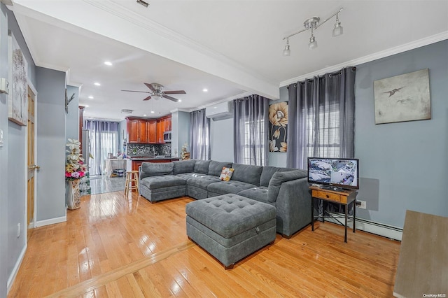 living room featuring ceiling fan, baseboard heating, crown molding, and light hardwood / wood-style flooring