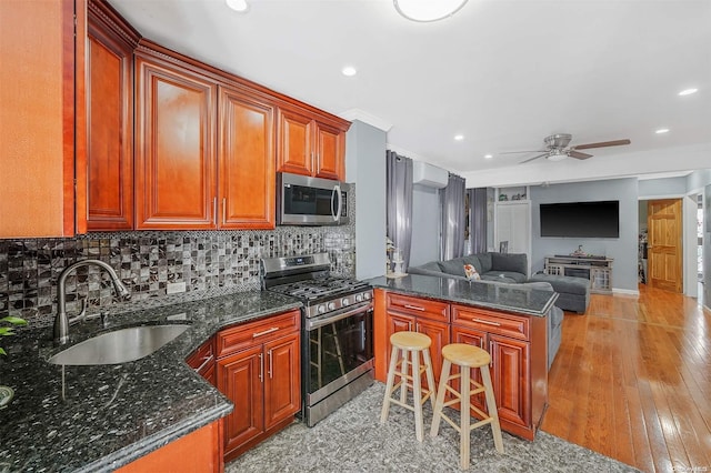 kitchen featuring ceiling fan, sink, stainless steel appliances, kitchen peninsula, and light wood-type flooring