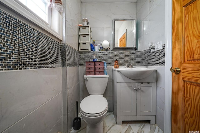 bathroom with vanity, toilet, and tile walls