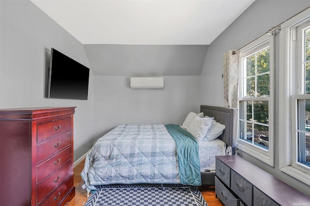 bedroom with light hardwood / wood-style floors, vaulted ceiling, and a wall unit AC