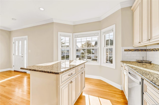 kitchen featuring dishwasher, a center island, cream cabinets, and light hardwood / wood-style flooring