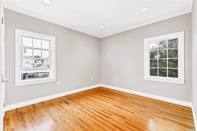 empty room with hardwood / wood-style floors, a wealth of natural light, and crown molding