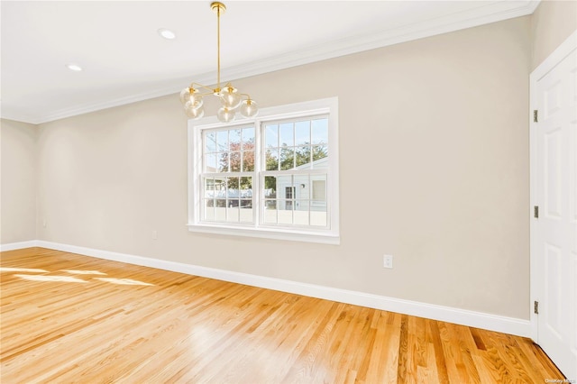 spare room with hardwood / wood-style flooring, ornamental molding, and a notable chandelier