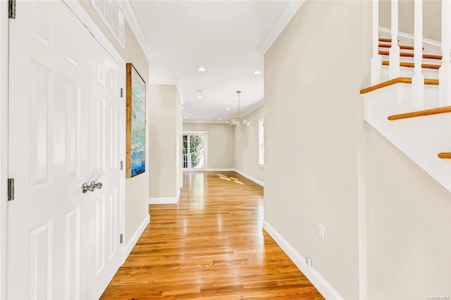 hallway with a chandelier, ornamental molding, and light hardwood / wood-style flooring