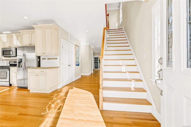 kitchen featuring tasteful backsplash, cream cabinets, light hardwood / wood-style flooring, and stainless steel appliances