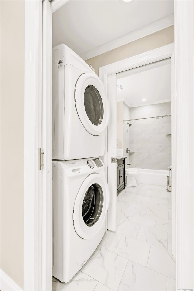 laundry area with ornamental molding and stacked washer / drying machine