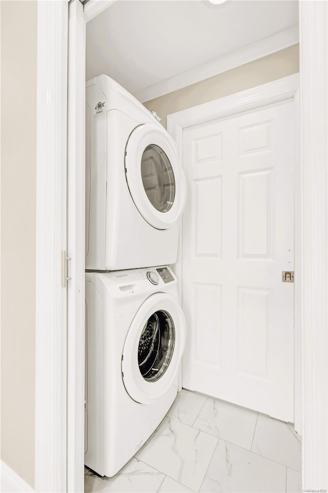 washroom featuring stacked washer and clothes dryer and ornamental molding