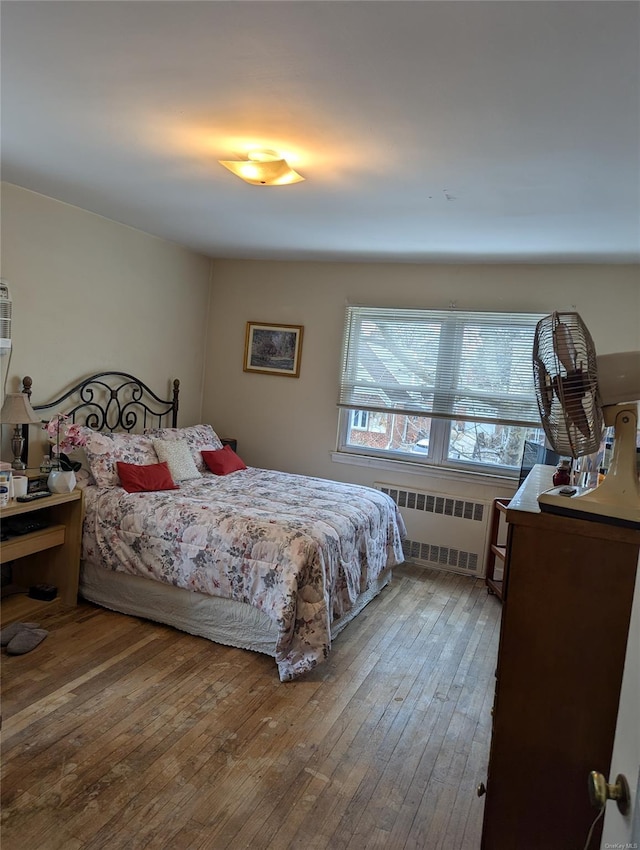 bedroom with radiator and hardwood / wood-style floors