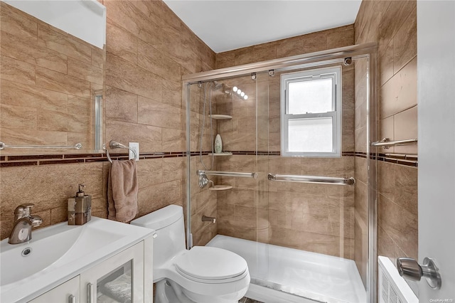 bathroom featuring an enclosed shower, vanity, toilet, and tile walls