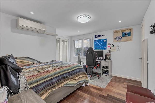 bedroom with a wall unit AC and hardwood / wood-style floors