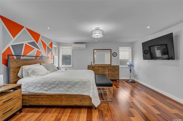 bedroom with a wall unit AC and dark hardwood / wood-style flooring