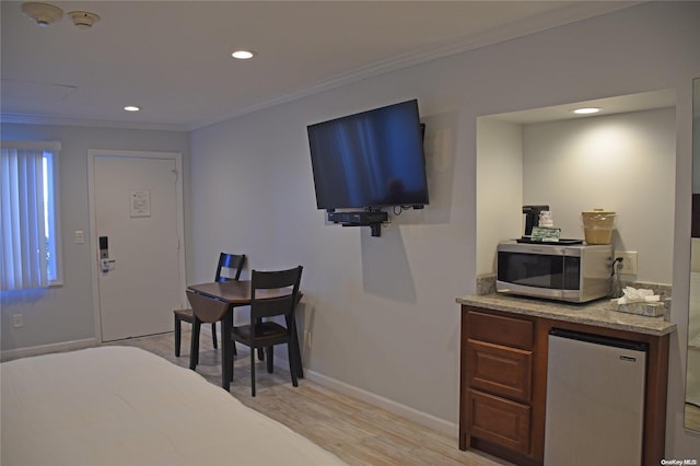 kitchen with appliances with stainless steel finishes, light hardwood / wood-style flooring, and ornamental molding