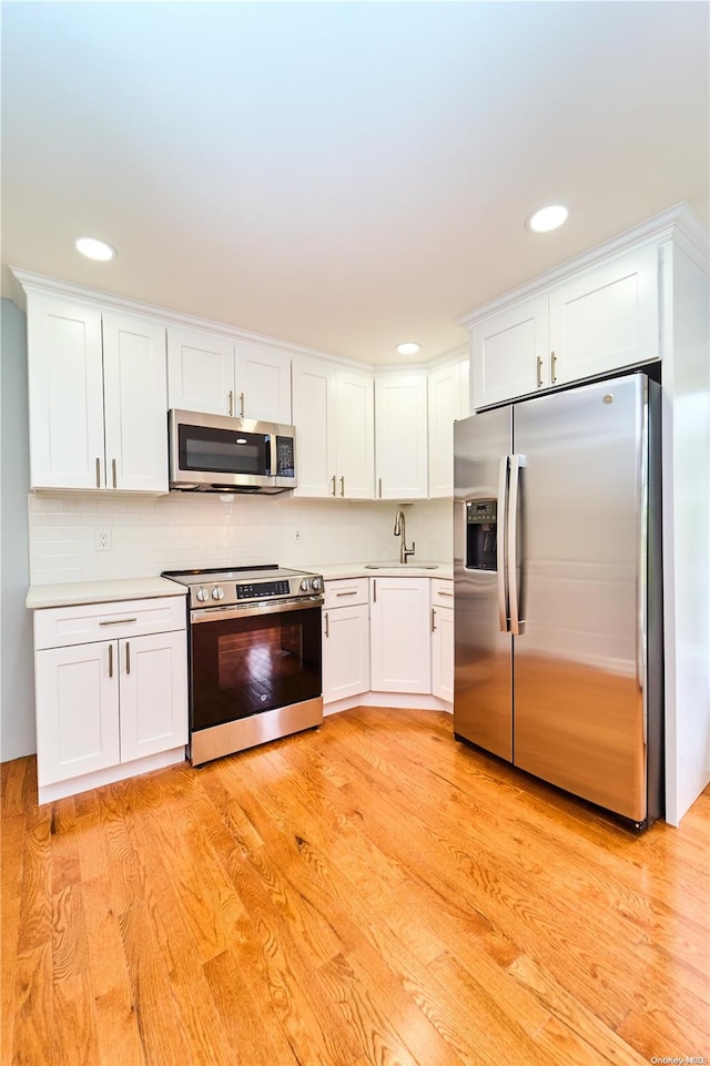 kitchen featuring white cabinetry, light hardwood / wood-style floors, and appliances with stainless steel finishes