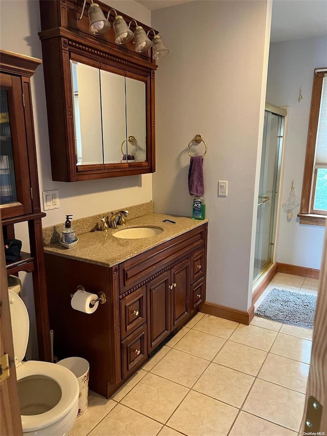 bathroom with tile patterned floors, vanity, a shower with shower door, and toilet