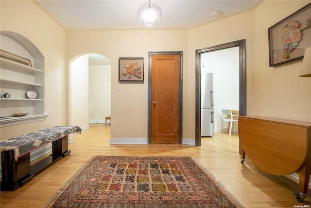 hall with built in shelves and light hardwood / wood-style flooring