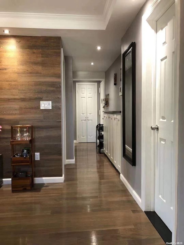 hallway with wood walls, dark hardwood / wood-style flooring, and crown molding