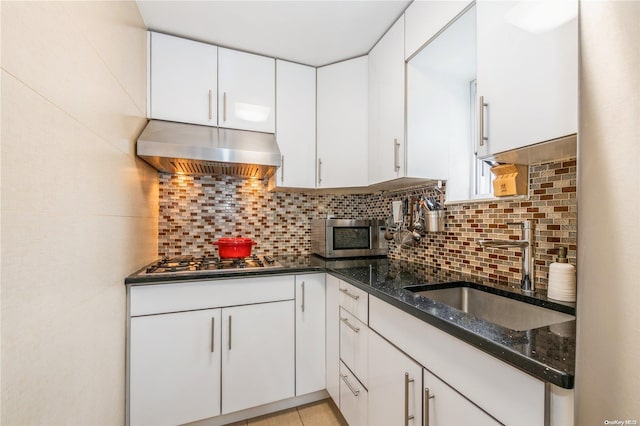 kitchen with white cabinetry, sink, stainless steel appliances, dark stone counters, and decorative backsplash