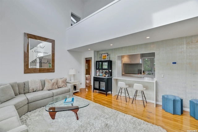 living room featuring a towering ceiling and light hardwood / wood-style flooring