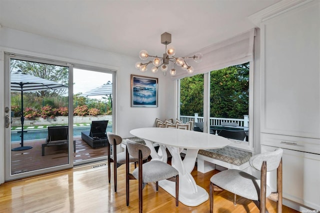 dining area with light wood-type flooring and an inviting chandelier