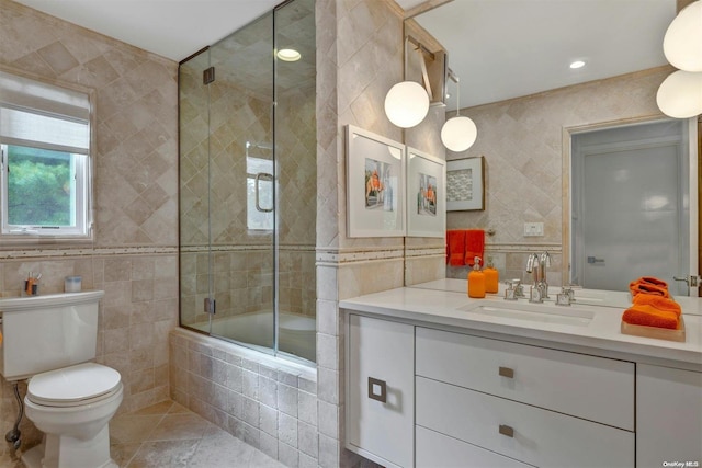 full bathroom with tile patterned flooring, combined bath / shower with glass door, toilet, vanity, and tile walls