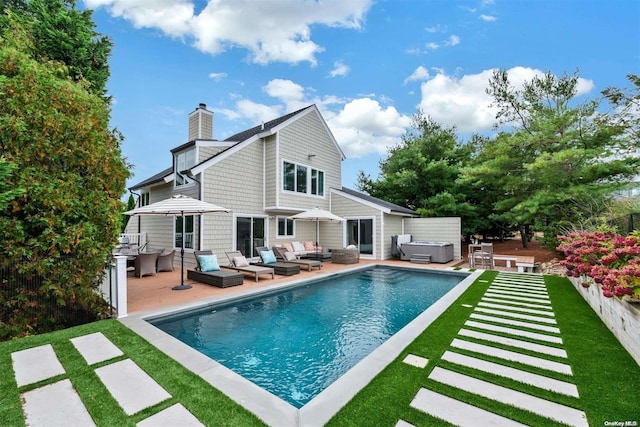 rear view of property featuring a patio area, an outdoor living space, and a swimming pool with hot tub