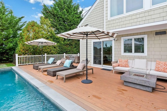 view of pool featuring an outdoor living space with a fire pit and a deck