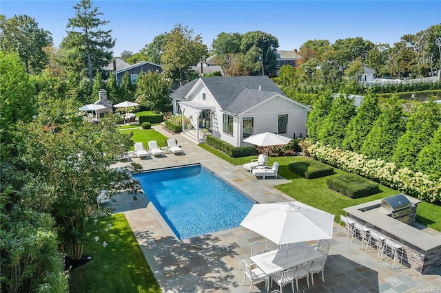 view of swimming pool with a patio area, a grill, and an outdoor kitchen