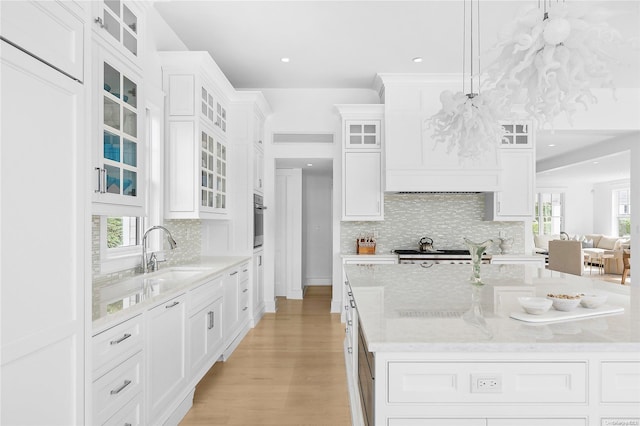 kitchen with backsplash, a center island with sink, white cabinets, sink, and appliances with stainless steel finishes