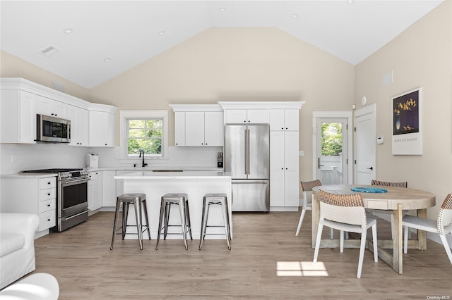 kitchen featuring white cabinets, a center island, stainless steel appliances, and light hardwood / wood-style flooring