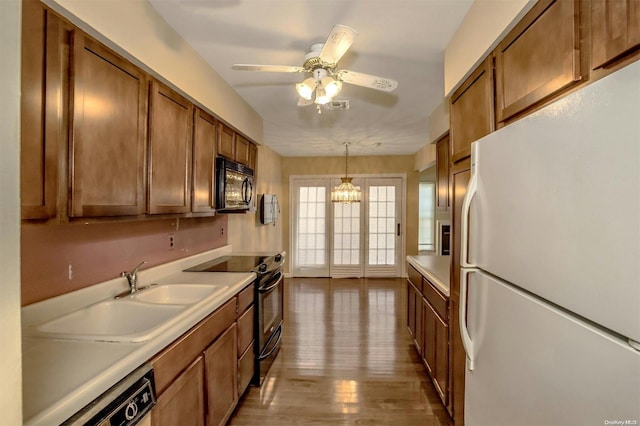 kitchen featuring ceiling fan with notable chandelier, sink, black appliances, decorative light fixtures, and light hardwood / wood-style floors