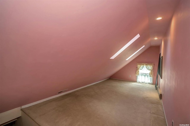 additional living space with light colored carpet and lofted ceiling with skylight