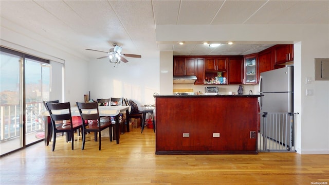 kitchen featuring kitchen peninsula, stainless steel fridge, ceiling fan, and light wood-type flooring