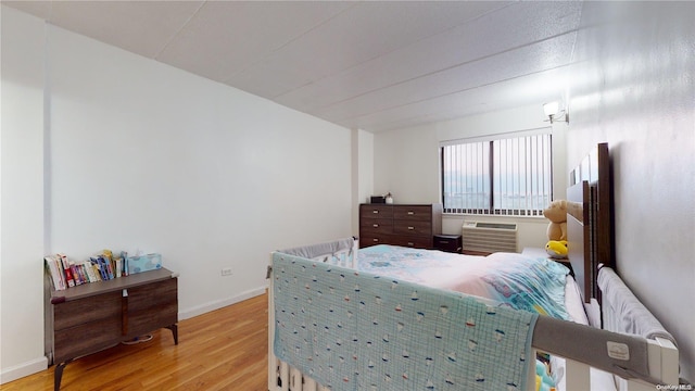 bedroom featuring light hardwood / wood-style floors, radiator heating unit, and a wall mounted AC