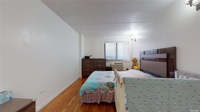 bedroom with an AC wall unit and hardwood / wood-style floors