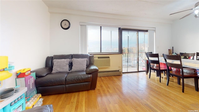 living room featuring a wall unit AC, ceiling fan, light hardwood / wood-style floors, and baseboard heating