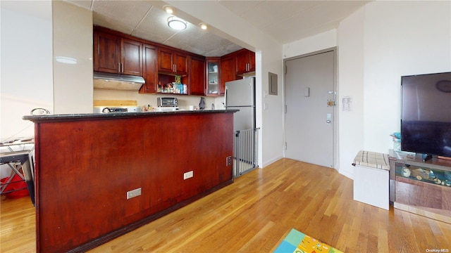 kitchen featuring stainless steel fridge, kitchen peninsula, and light hardwood / wood-style flooring