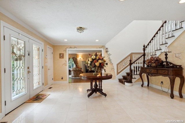 tiled entryway with french doors, a textured ceiling, and crown molding