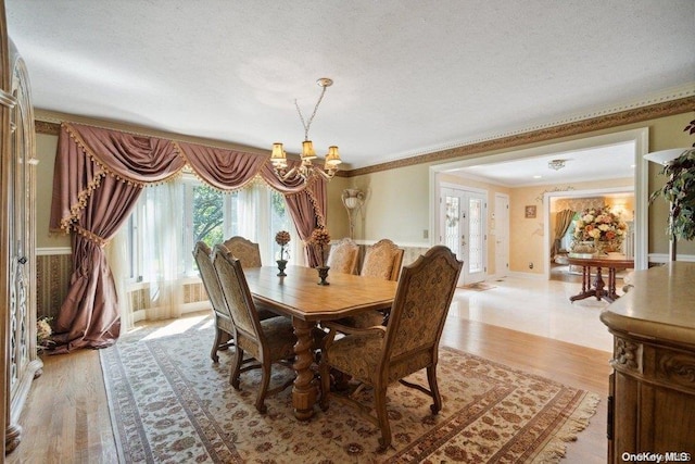 dining area with crown molding, light wood-type flooring, and a textured ceiling