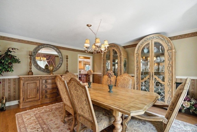 dining room featuring wood-type flooring, an inviting chandelier, and ornamental molding